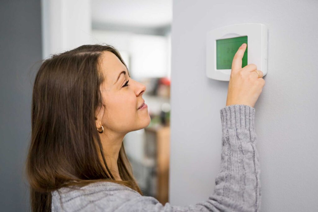 Woman adjusting her thermostat