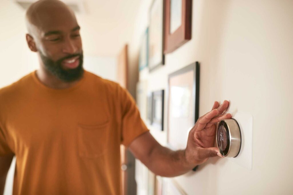 Man adjusting his thermostat in his Odenton home