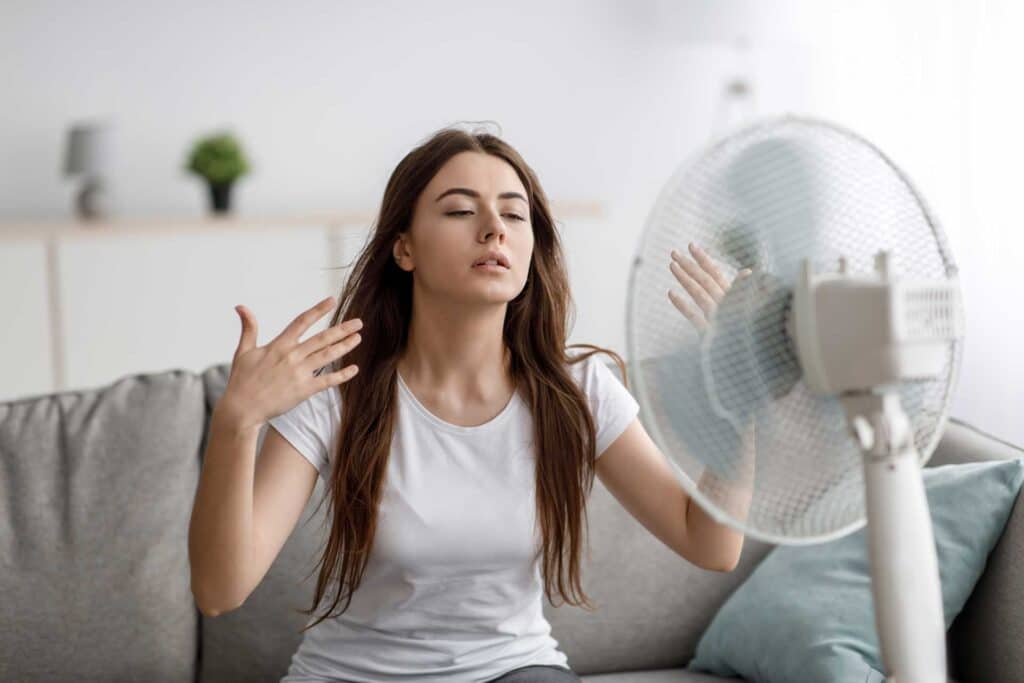 Woman using a fan because she's hot and her air conditioner isn't working